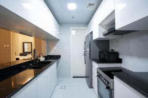 a kitchen with black counter tops and white appliances at One Bedroom Apartment at MAG214 JLT by ANW Vacation Homes in Dubai