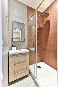 ein Bad mit einer Dusche, einem Waschbecken und einem Spiegel in der Unterkunft Appartement proche Parc Monceau - II in Paris