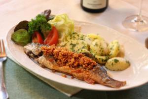 un plato de comida con pescado y verduras en una mesa en Apartment Haus Toplitzsee nahe dem Grundlsee und Toplitzsee, en Gössl