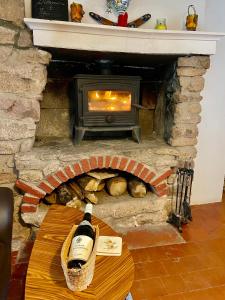 a bottle of wine sitting on a table in front of a fireplace at Maison du petit Poète in Quarré-les-Tombes