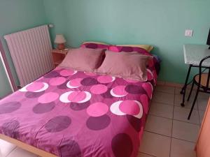 ein Bett mit einer rosa Tagesdecke mit rosa Polka-Punkten in der Unterkunft LE PETIT VERMONDOIS in Le Bacon