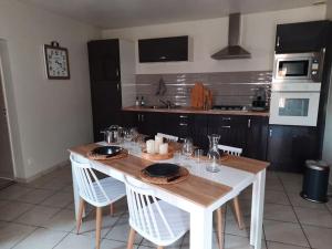 eine Küche mit einem Holztisch mit weißen Stühlen und eine Küche mit in der Unterkunft L'écrin de verdure à 25 minutes du Puy du Fou in Cerizay