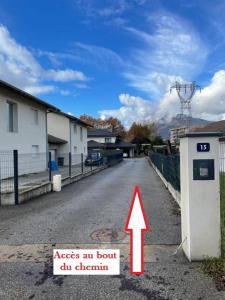 a road with a sign with an arrow next to a building at Studio bien situé & tout équipé dans une maison in Scionzier