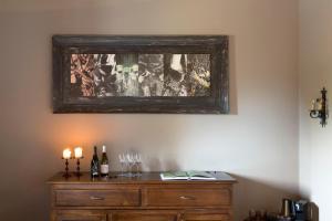 une peinture au-dessus d'une commode avec deux bougies et des verres à vin dans l'établissement Casa Arrigo, à Linguaglossa