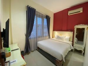 - une chambre avec un lit blanc et un mur rouge dans l'établissement JIYO BOUTIQUE HOTEL by SAJIWA, à Medan