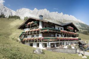 a building on a hill with mountains in the background at Alpengasthof-Hotel Kopphütte in Mühlbach am Hochkönig