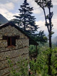 a stone building with a tree in the background at Castaway Offbeat Stay in Manāli