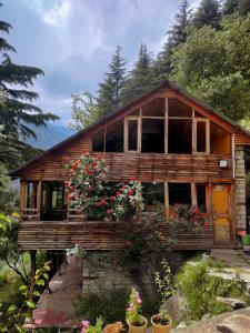 a wooden house with flowers in front of it at Castaway Offbeat Stay in Manāli
