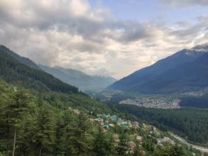 a view of a valley with a town and mountains at Castaway Offbeat Stay in Manāli