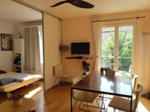 a living room with a dining table and a television at Central quiet and cosy apartment near Hallenstadion in Zurich