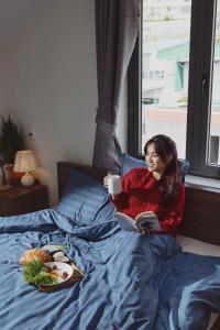 une femme qui se couche au lit avec un livre et une tasse de café dans l'établissement Nhà Giáng Sinh Trên Đồi Villa, à Đà Lạt