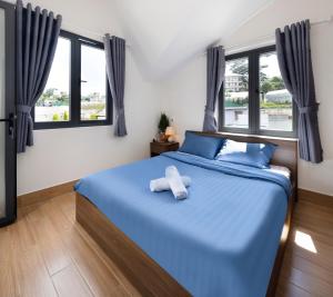 een slaapkamer met een blauw bed met 2 handdoeken erop bij Nhà Giáng Sinh Trên Đồi Villa in Da Lat