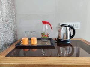 una cafetera y dos tazas en una mesa en Lemon Hotels, en Jamshedpur