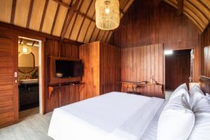 a bedroom with a white bed and a television at DADEKA Canggu in Canggu