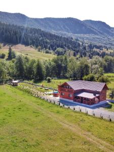 a barn in the middle of a field with a house at Cabana Dintre Munti in Vidra