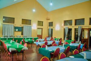 una sala con tavoli e sedie con tavoli verdi e rossi di UPENDO SAFARI LODGe a Karatu