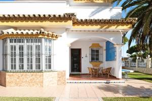 uma casa branca com um alpendre e uma mesa em Chalet con Piscina y Barbacoa 4 d em Chiclana de la Frontera