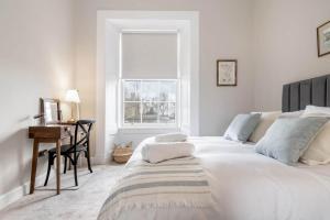 una camera bianca con letto, scrivania e finestra di Skye Sands - 11 Alexandra Penthouse - St Andrews a St Andrews