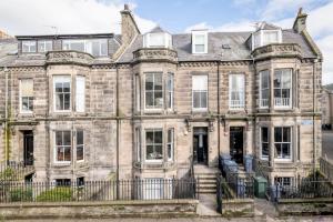 an old stone house with a fence in front of it at Skye Sands - 11 Alexandra Penthouse - St Andrews in St. Andrews