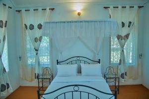 una camera da letto con letto blu e tende bianche di UPENDO SAFARI LODGe a Karatu