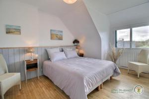 een witte slaapkamer met een bed en 2 stoelen bij Beg ar lann in Pleumeur-Bodou