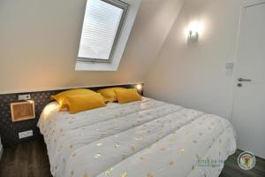 - une chambre avec un lit doté d'oreillers jaunes et d'une fenêtre dans l'établissement La terrasse sur le golf, à Pleumeur-Bodou