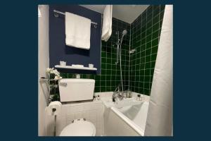a green tiled bathroom with a toilet and a tub at Palm Studio in London