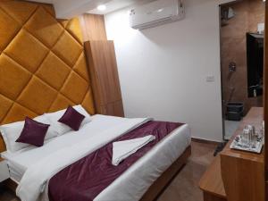 um quarto com uma cama grande com almofadas roxas e brancas em Hotel Era em Ahmedabad