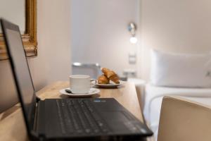 a laptop computer on a table with a cup of coffee and pastries at Piraeus City Hotel in Piraeus