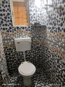 łazienka z toaletą i ścianą wyłożoną kafelkami w obiekcie Matoshree Nivas w mieście Lohogaon