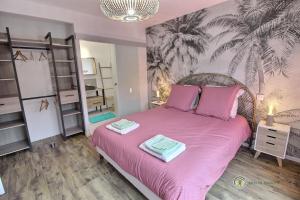a bedroom with a pink bed with two towels on it at Le petit marius in Pleumeur-Bodou
