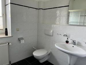 a white bathroom with a toilet and a sink at Wiehengebirgs Fernblick App 2 in Bad Essen
