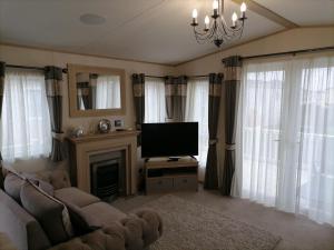 a living room with a television and a fireplace at Alberta Holiday Park in Seasalter