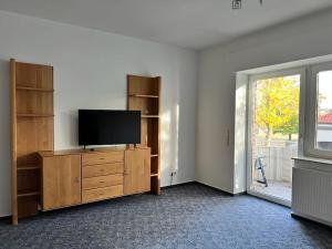 a living room with a television on a wooden dresser at Wiehengebirgs Fernblick App 2 in Bad Essen