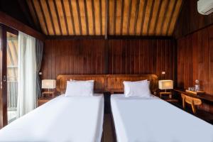 deux lits dans une chambre aux murs en bois dans l'établissement Cove Dadeka, à Canggu