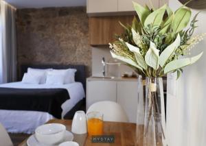 a vase with flowers on a table in a bedroom at MyStay - D Maria Apartments in Vila Nova de Famalicão