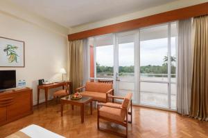 Inya Lake Hotel في يانغون: غرفة مع غرفة معيشة مع نافذة كبيرة