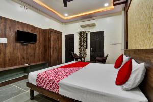 a bedroom with a bed with red pillows and a tv at OYO Flagship Hotel Lux Inn in Udaipur