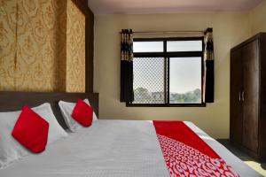 a bedroom with a bed with red pillows and a window at OYO Flagship Hotel Lux Inn in Udaipur
