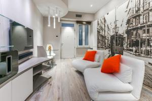 un soggiorno con 2 divani bianchi e cuscini arancioni di [DUOMO 14 min] Orange Milano M3 a Milano