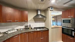 a kitchen with wooden cabinets and a stove top oven at Centaurus Apartment Mountain View Three Bed in Islamabad