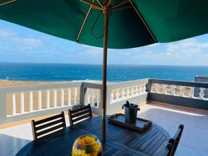 a table with an umbrella on a balcony with the ocean at Residencial Sol Point Art in Ponta do Sol