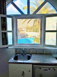 a kitchen sink with a window with a view of a pool at The Best in Perissa