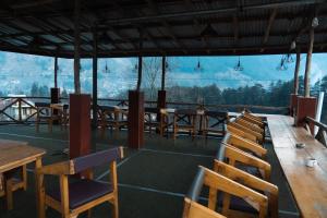 a restaurant with wooden tables and chairs with a view at Jungle by sturmfrei Manali in Manāli