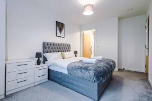 a bedroom with a large bed and a dresser at Luxury balcony apartment near Manchester City Centre - Free Secure Parking - Self-Check In in Manchester