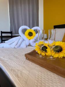 ポンタ・ド・ソルにあるResidencial Sol Point Artのベッドの上にひまわりとワイングラスを用意したテーブル