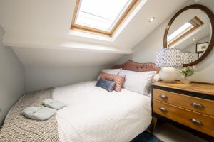 a bedroom with a bed with a mirror and a dresser at Kitten Cottage in West Witton