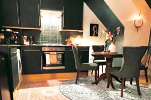 une cuisine avec des armoires vertes, une table et des chaises dans l'établissement The Maple Retreat - Hampstead, à Londres