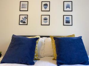 a bedroom with blue pillows and framed pictures on the wall at Stylish Apartments near the sea front at Morecambe in Heysham