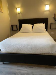 1 cama grande con sábanas blancas y 2 almohadas en Logis Hôtel Le Clement V, en Roquemaure